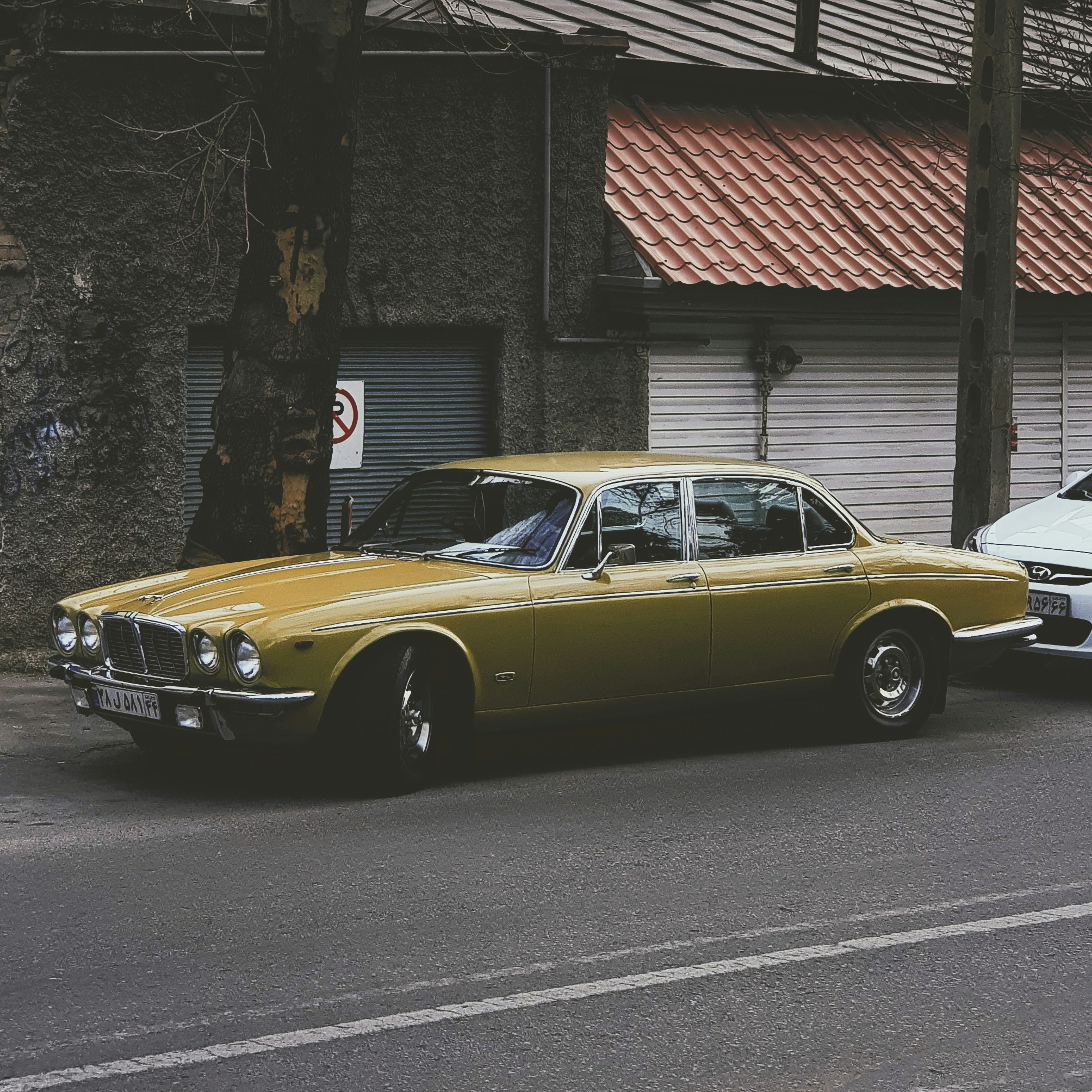 Gold classic Jaguar E-Type on a sunlit street