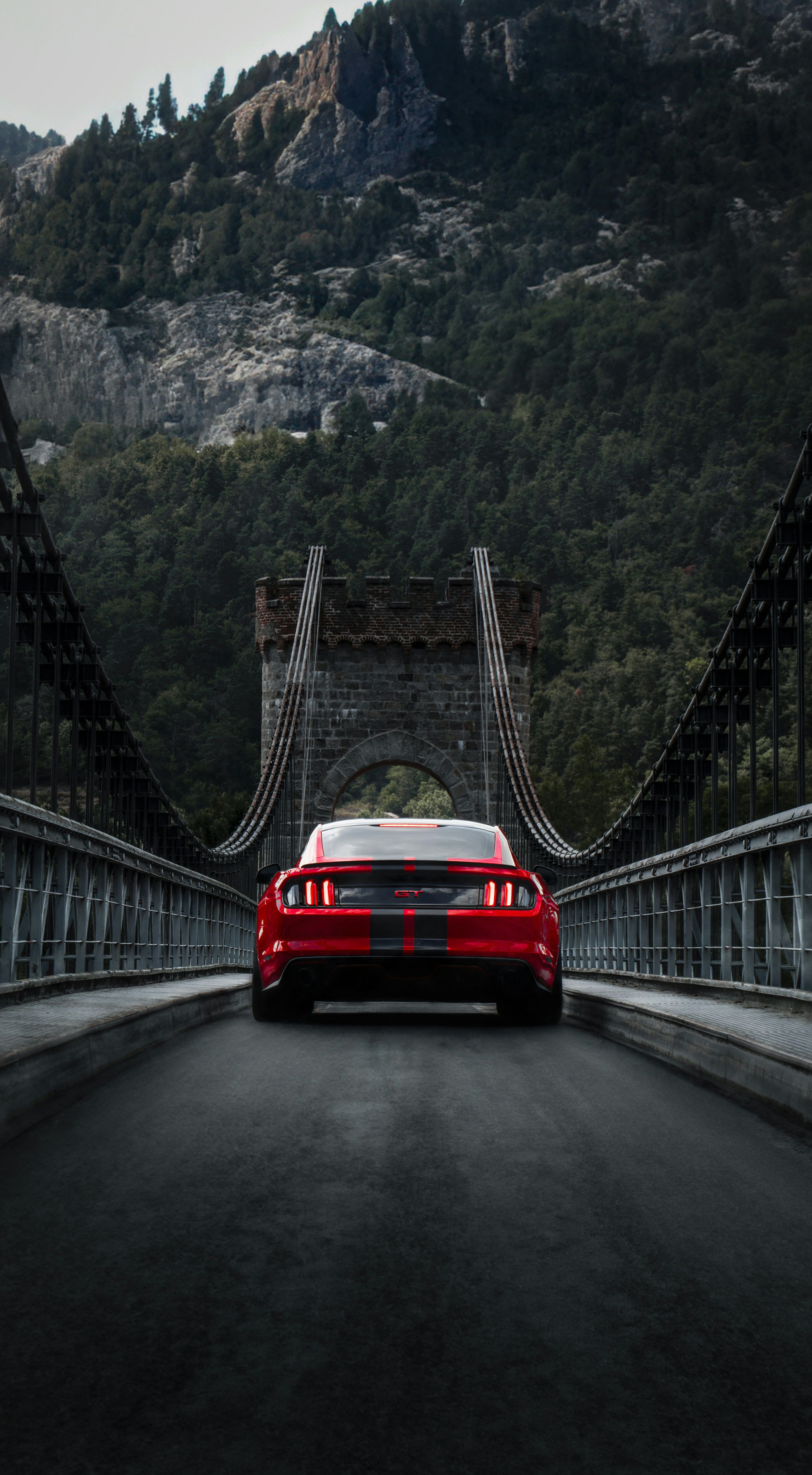 Red Mustang on an industrial bridge with dramatic sky